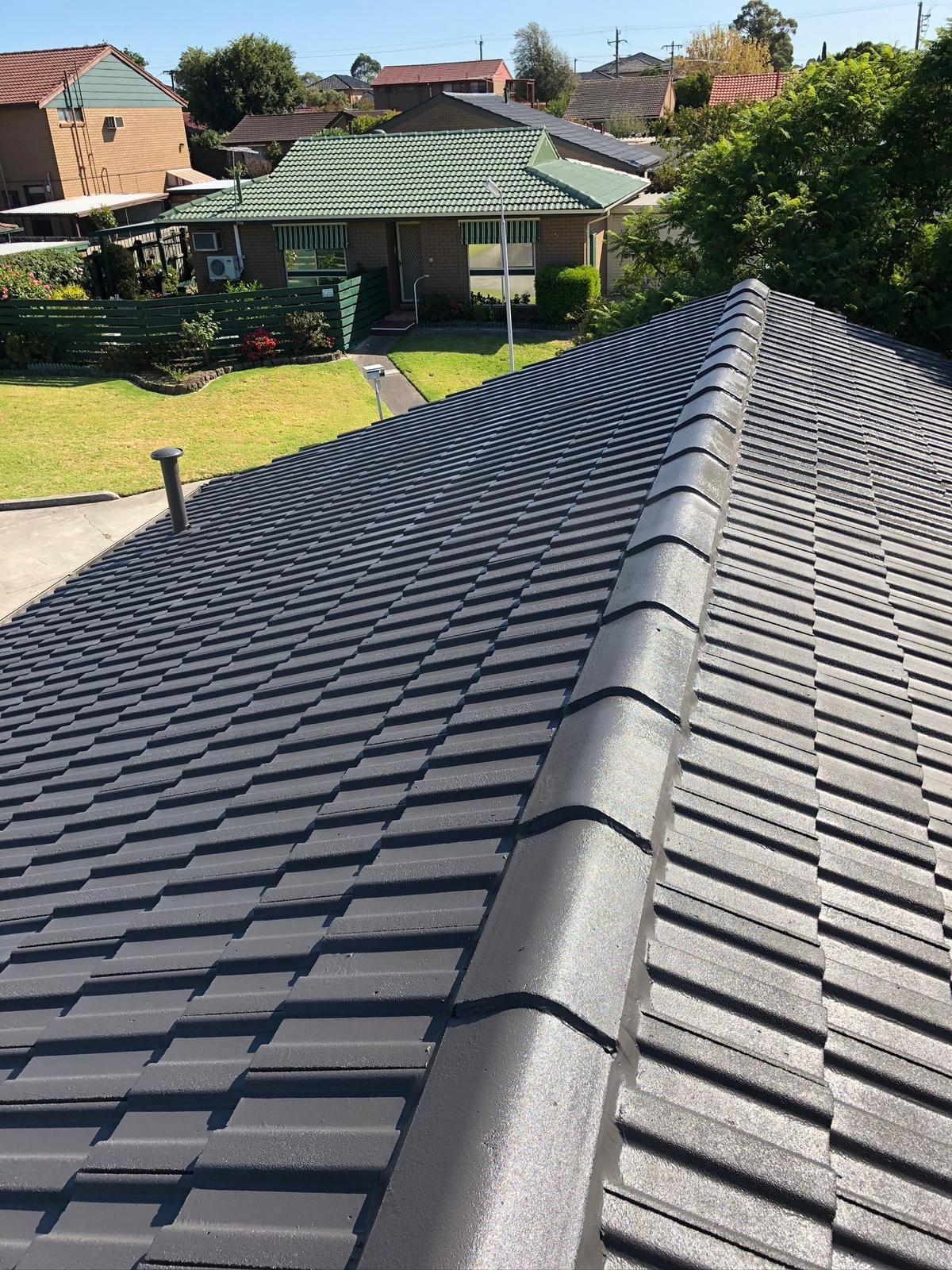 View of a newly installed modern tile roof with houses and gardens in the background.